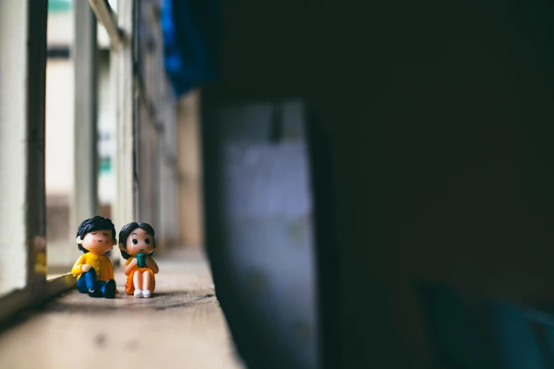 two toy children sitting beside each other in a hallway