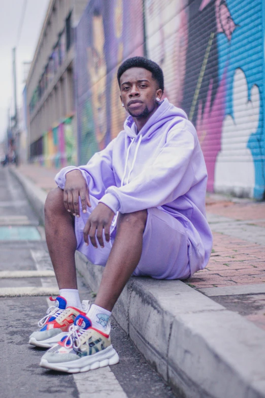 a man sitting in the street, dressed in a hoodie and nike sneakers