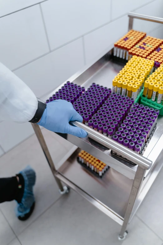 a worker with a glove is picking up a rack full of lego blocks