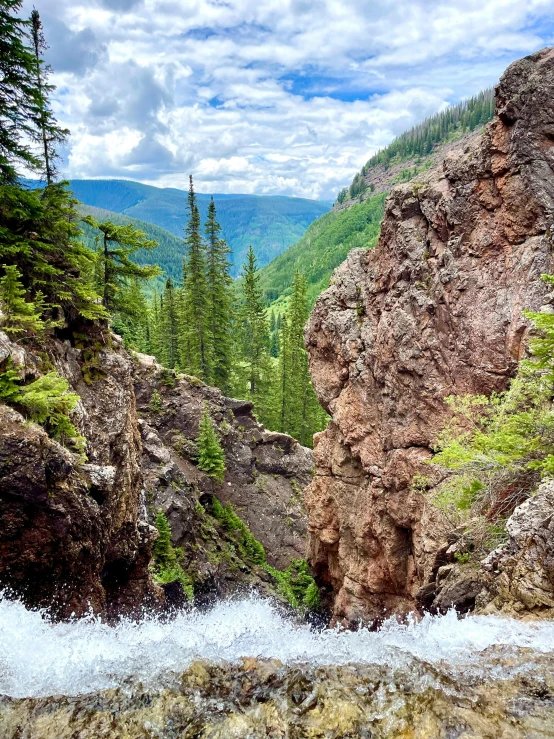 a river is flowing from a large rocky hillside