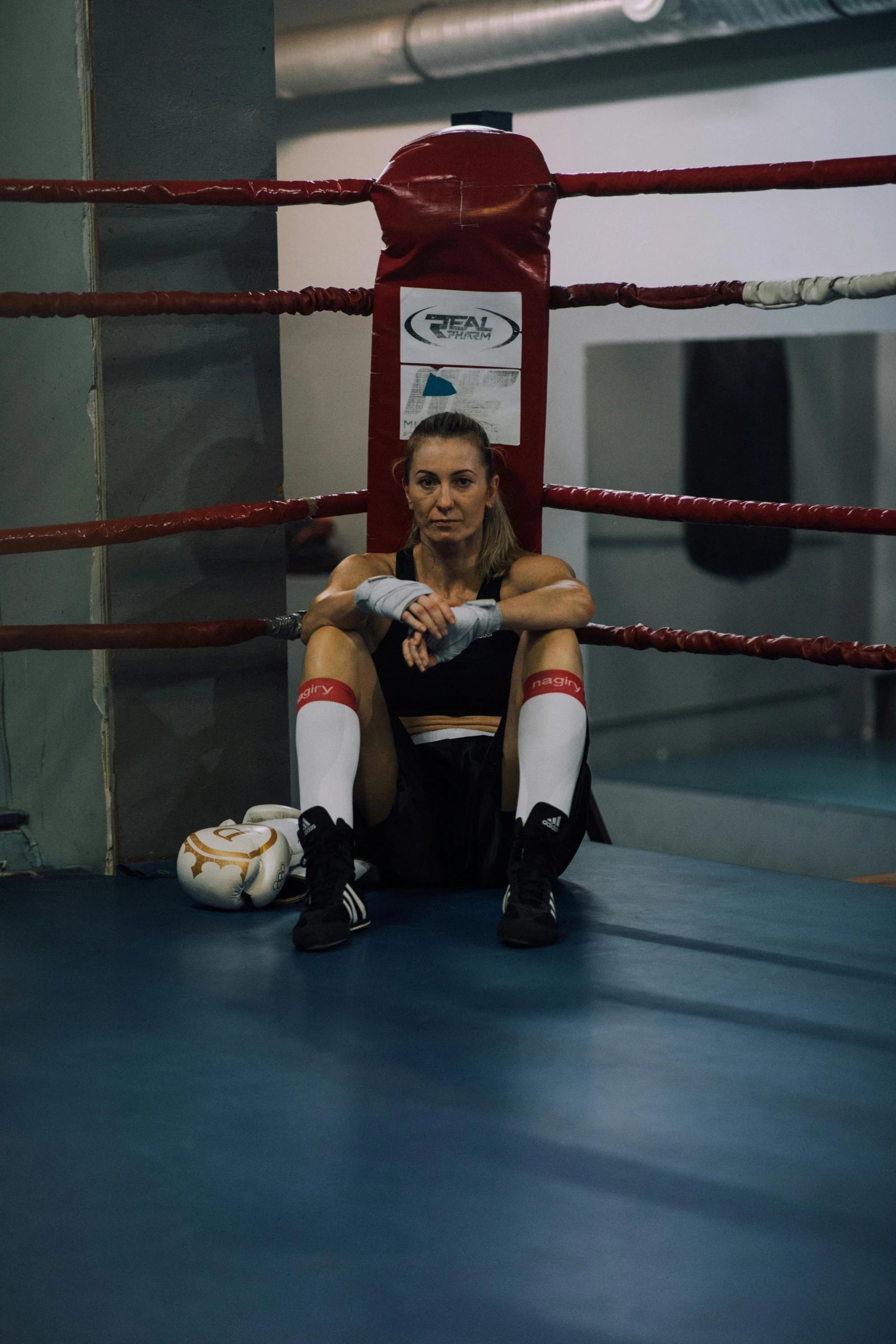 woman sits in corner of boxing ring waiting for the punch