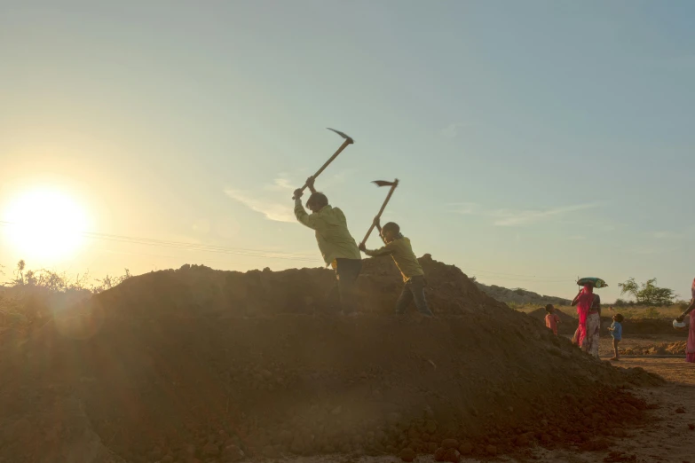 four people are shoveling some dirt into a pile