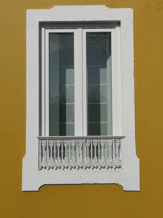 a yellow building with a white balcony and window