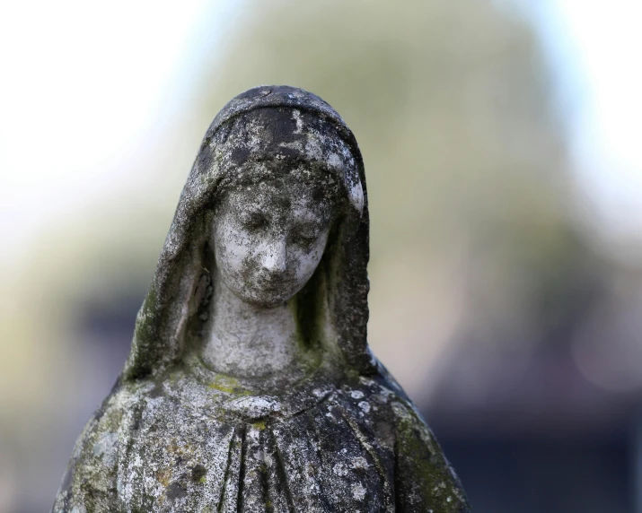 a statue with one eye open is covered in moss