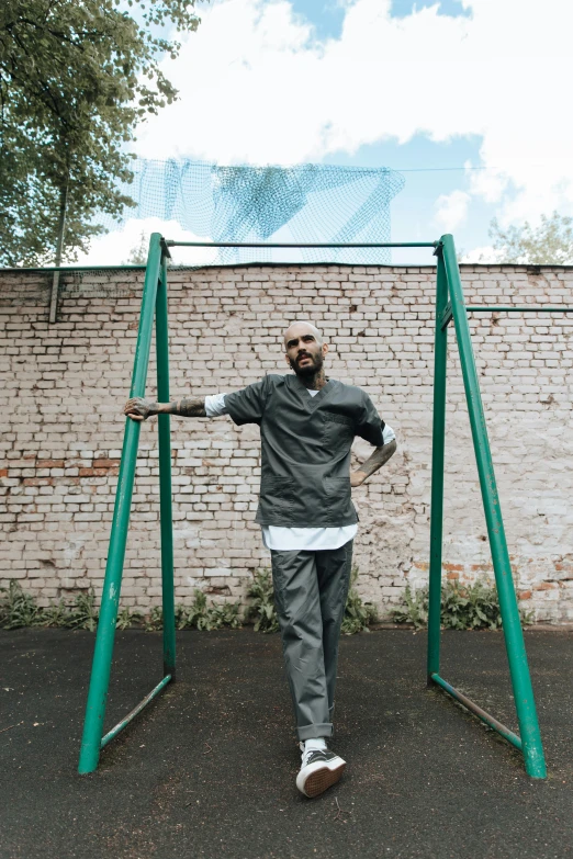 man standing on a large gym swing holding hands above his head