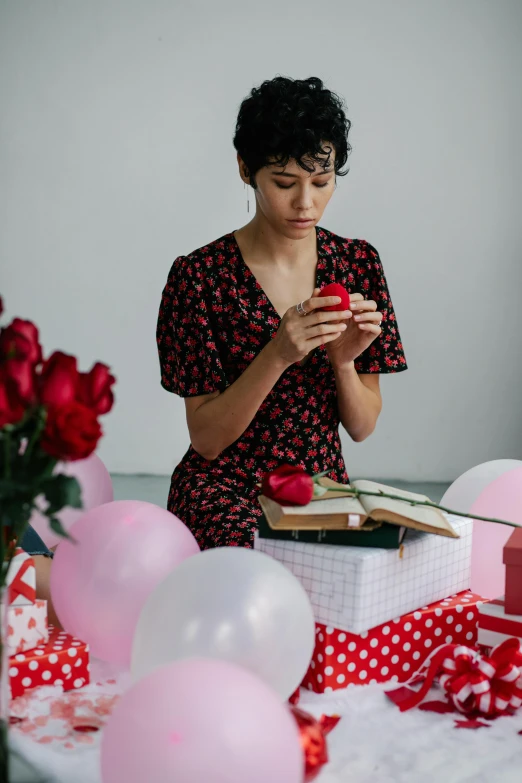 a woman sitting down with balloons and an open book