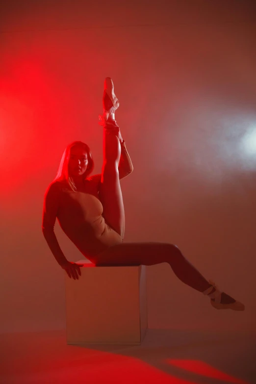 a woman posing in front of a red spotlight on a cube with her 