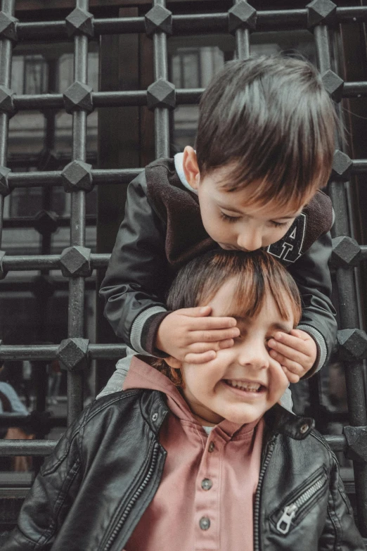 two little boys that are standing on each other