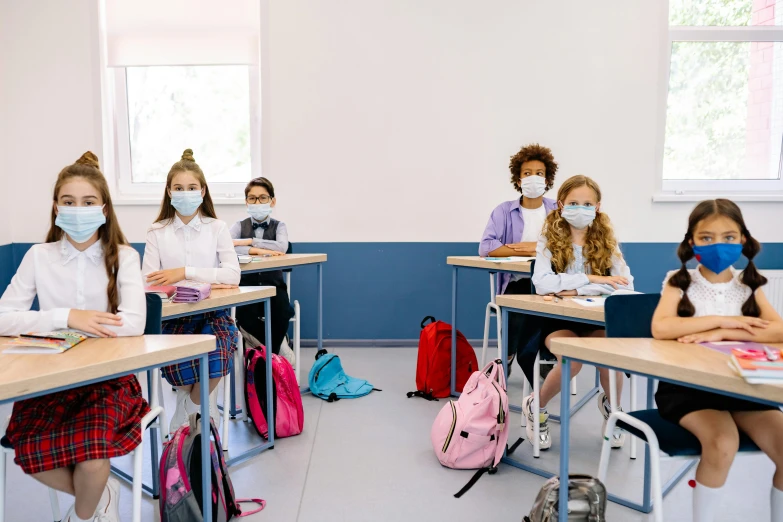 school children wearing face masks while sitting at desks