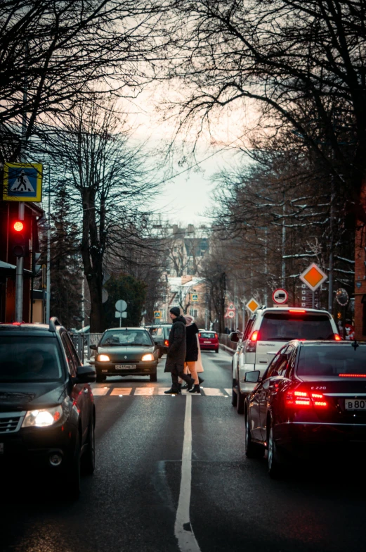the view from the road shows people crossing and cars on the street