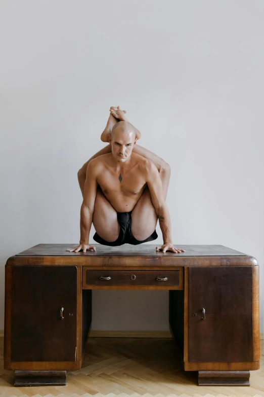 a man in underwear sitting at a desk with one hand on his head