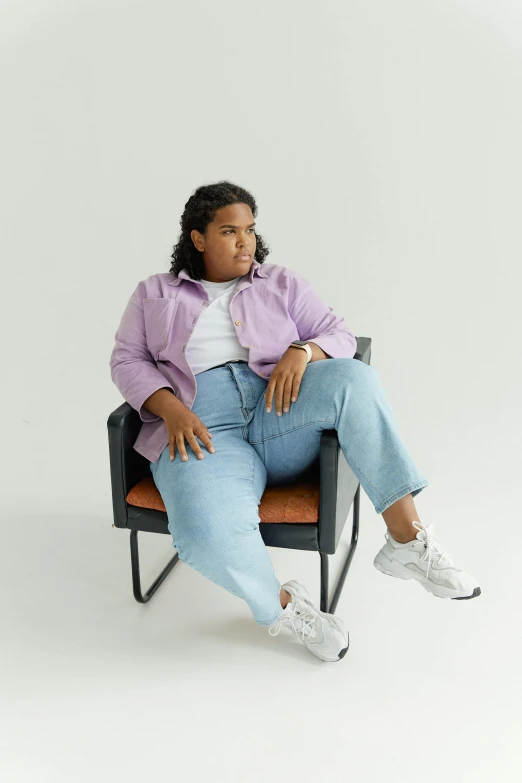 the woman is sitting in a chair wearing a purple jacket