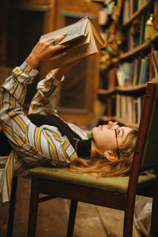 the girl lays down on her back reading a book