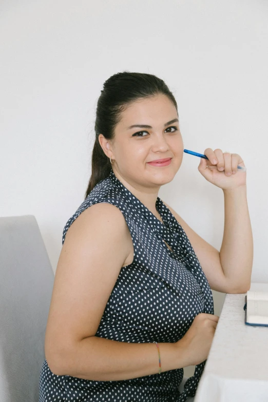 a woman is posing while she has a blue pen