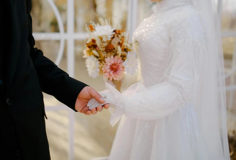 the bride and groom hold hands with a bouquet of flowers
