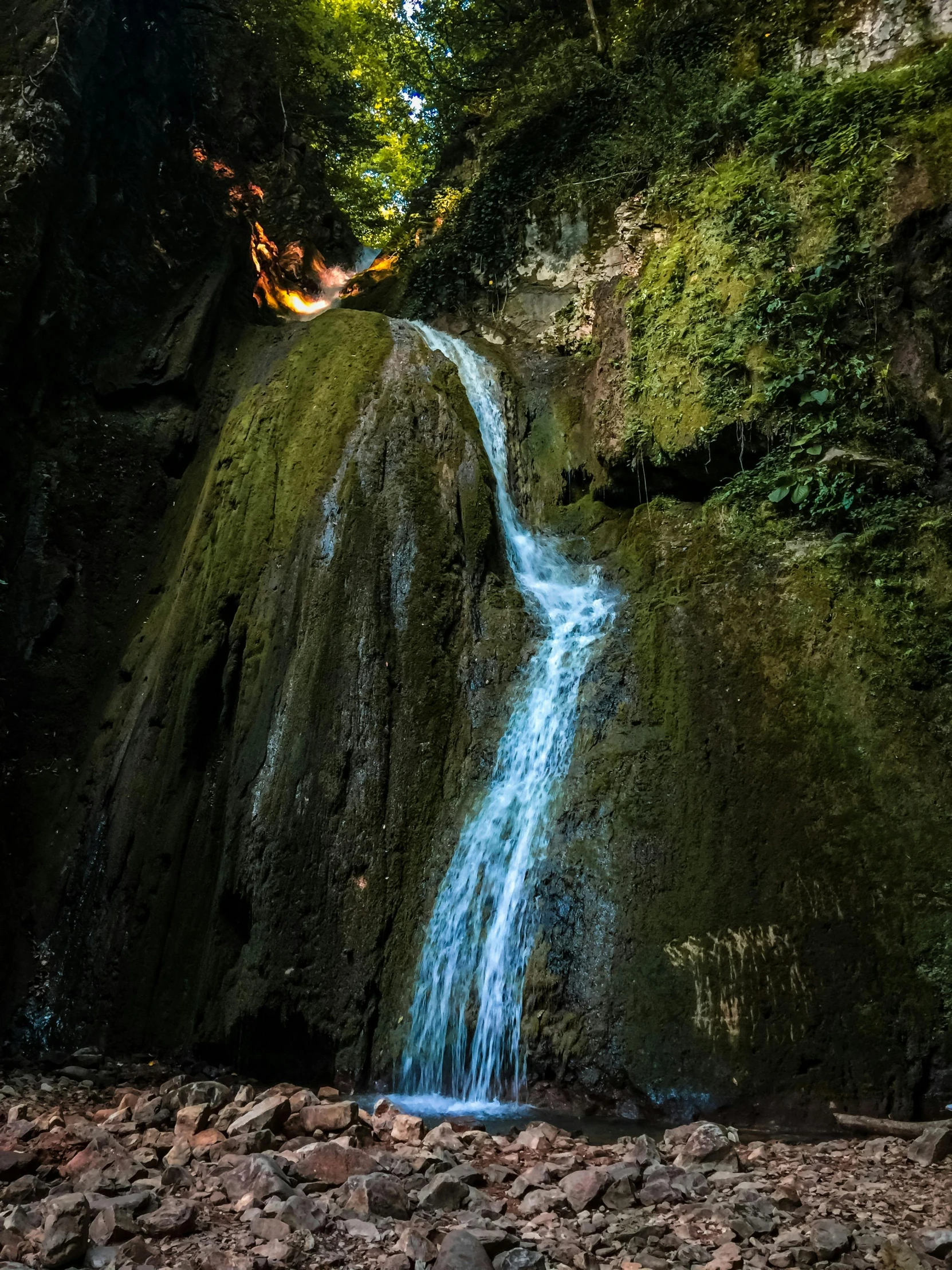 a view of a small waterfall with rock walls