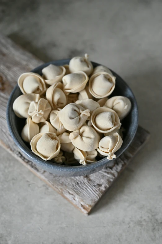 peeled mushrooms in a grey bowl on wooden board