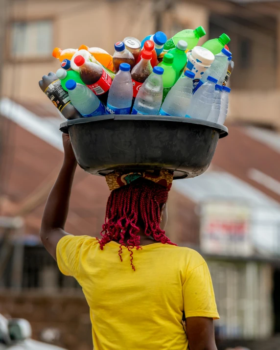 woman carrying tray full of bottle containers on her head