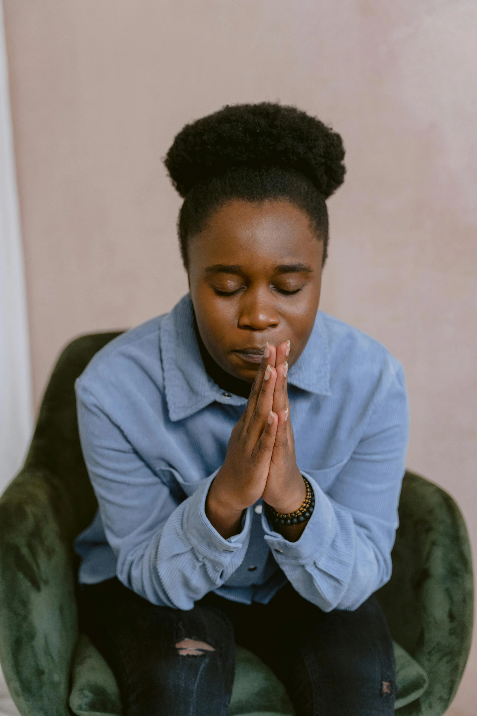 a woman sitting in a chair while holding her hands together