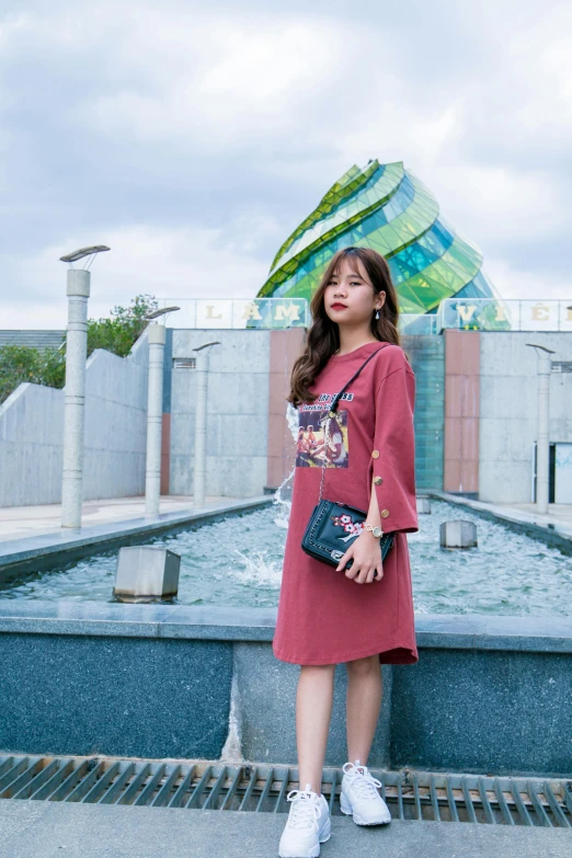 a woman is standing by some water with a bag on her shoulder