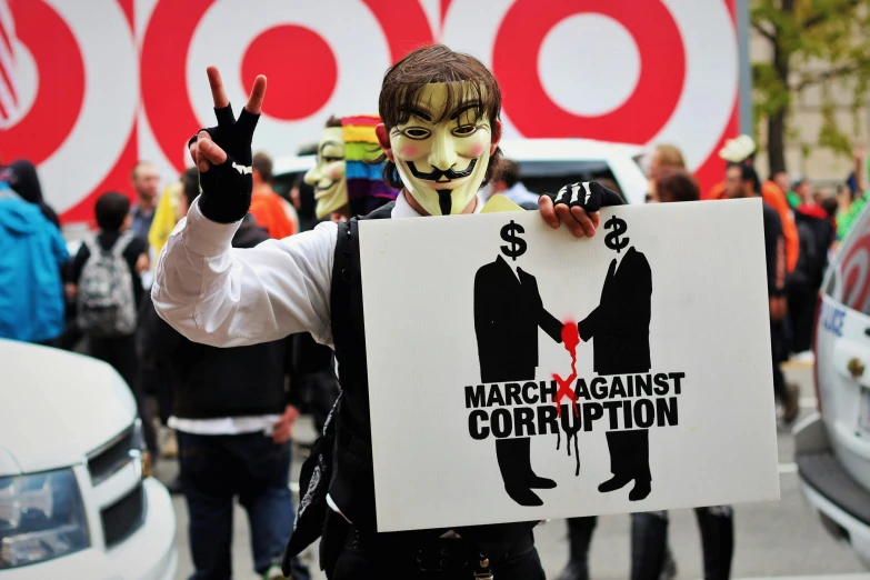 a man holding up a cardboard sign during a protest