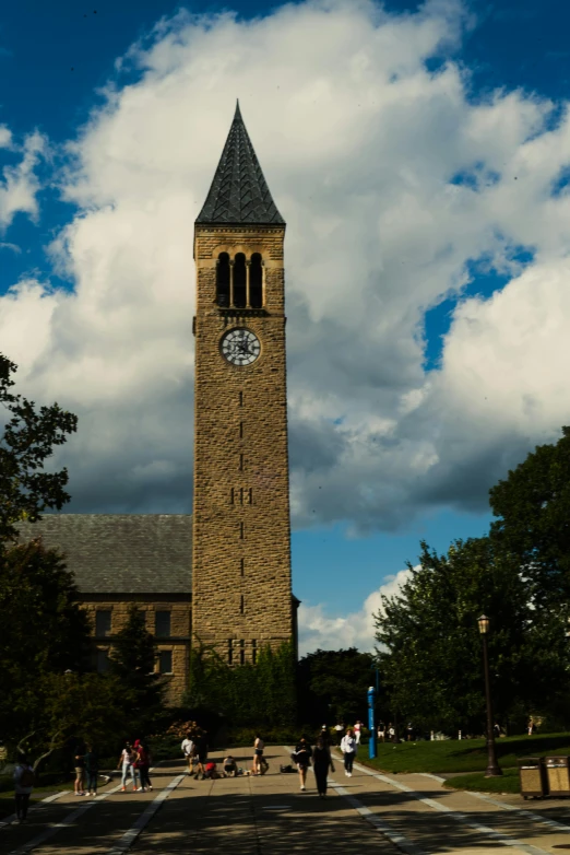 people walking towards a tall tower with a clock on it