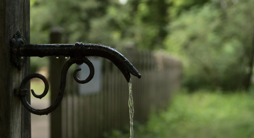 an iron handle on a fence post is next to a small green field