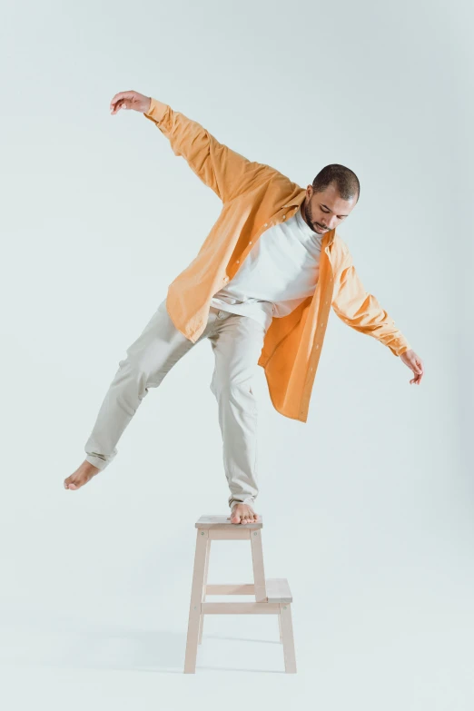 a man with an orange jacket standing on top of a chair