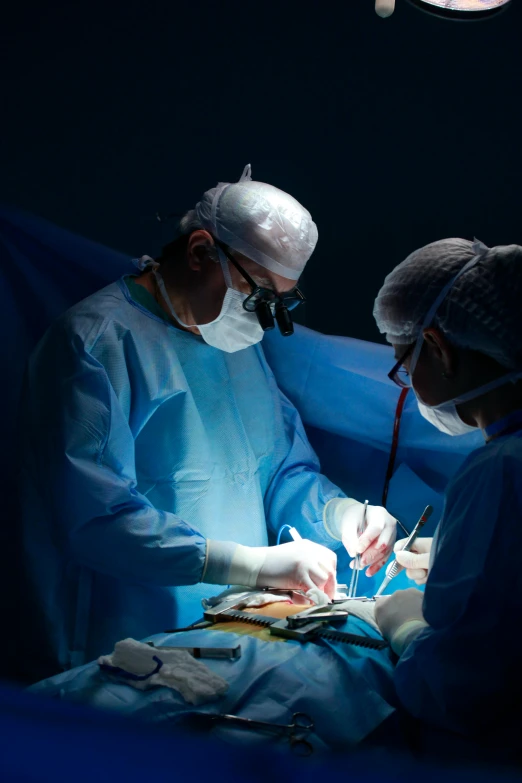 two medical professionals performing  on a man in a blue gown