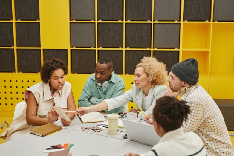 five people sitting around a table discussing soing