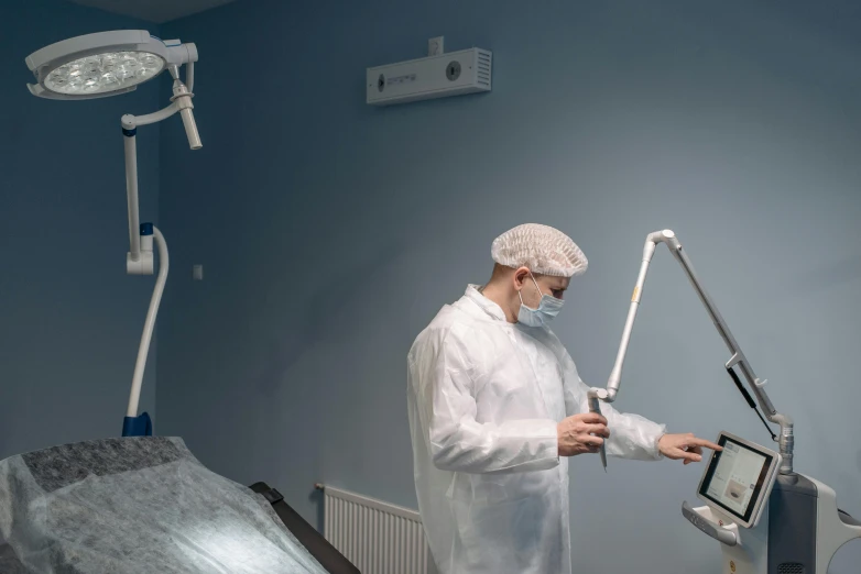 a man in a white lab coat using a cellphone in front of an open laptop