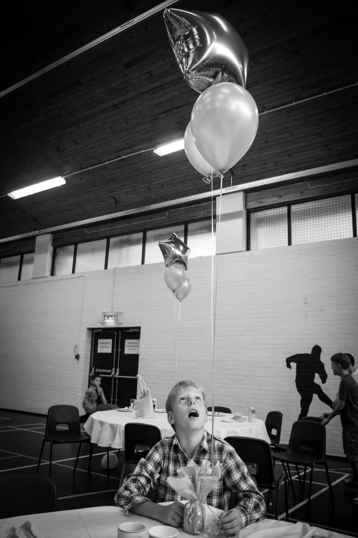 the man smiles as balloons fly over him