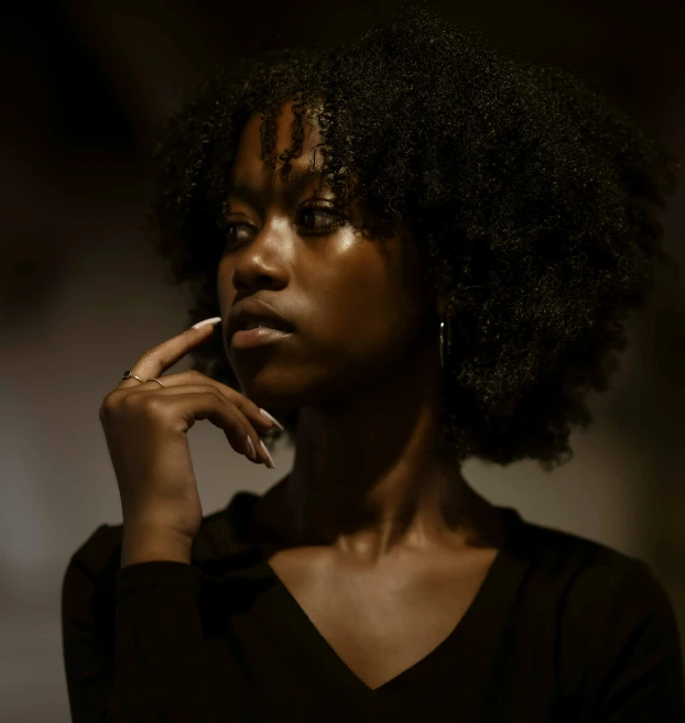a black woman looking to the side with her finger on her lip