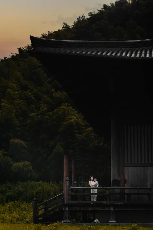 two people standing on a wooden porch at sunset