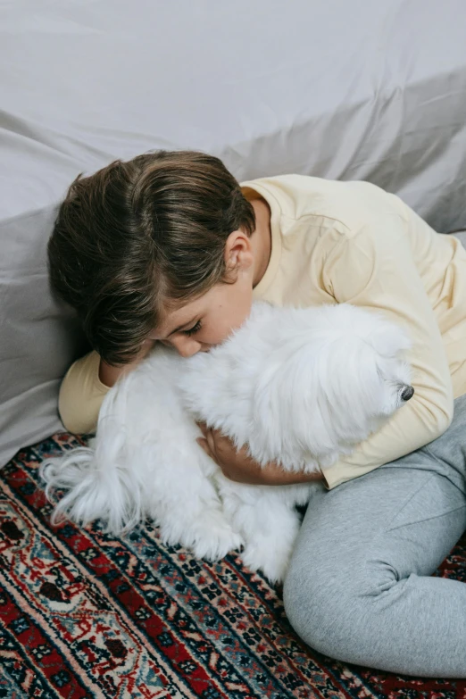 a little girl is hugging a white dog