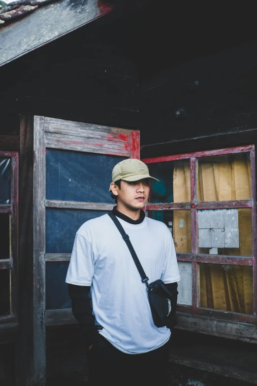 a man in a baseball cap leaning against a building