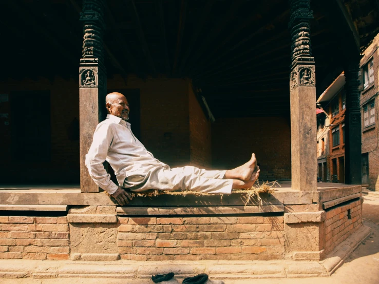 the old man is wearing white clothes sitting on some stairs