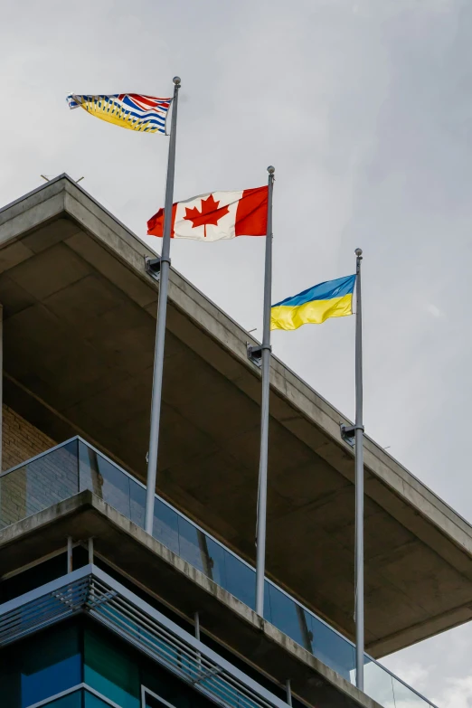 the flag of canada and the canadian flag fly outside of a building