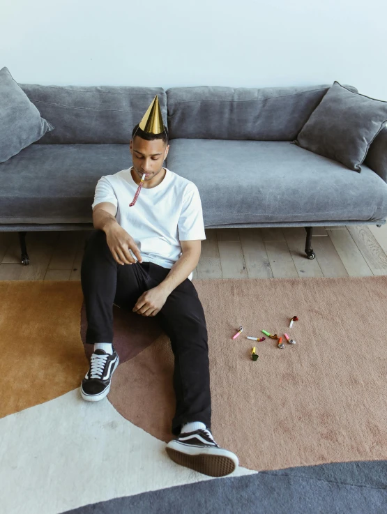 a man sitting on a floor with a birthday hat