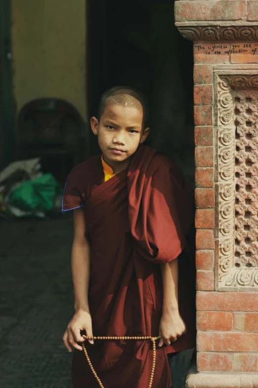 a young monk dressed in red robes is holding onto a piece of rope