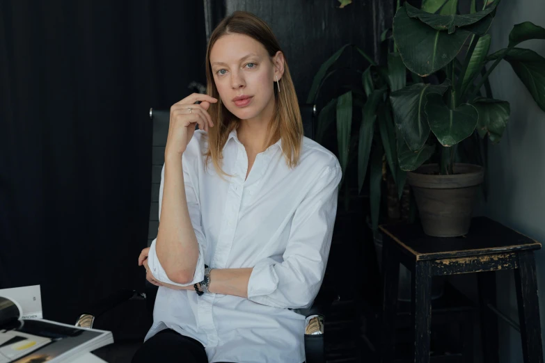 woman in white shirt talking on phone at table with potted plant