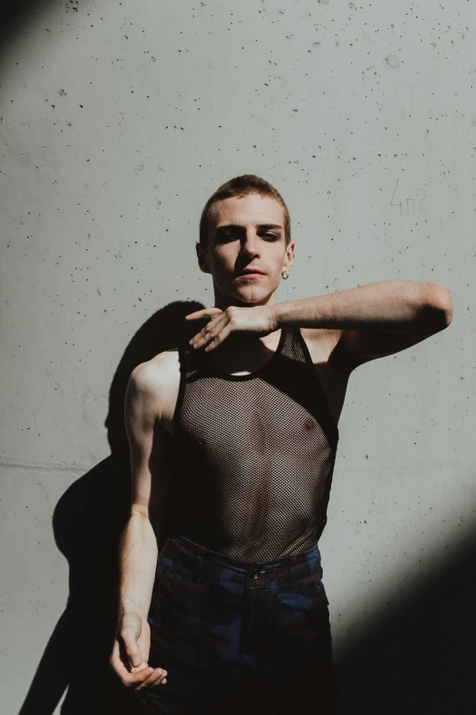 a man in tank top standing in front of a white wall