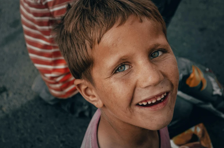 a child smiling at the camera, with a striped backpack in the background