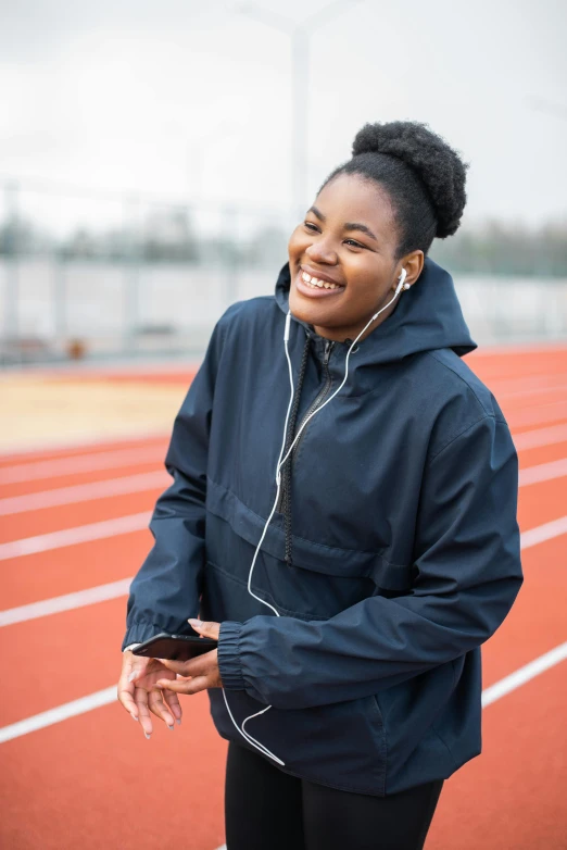 a woman with earbuds on and standing in a track