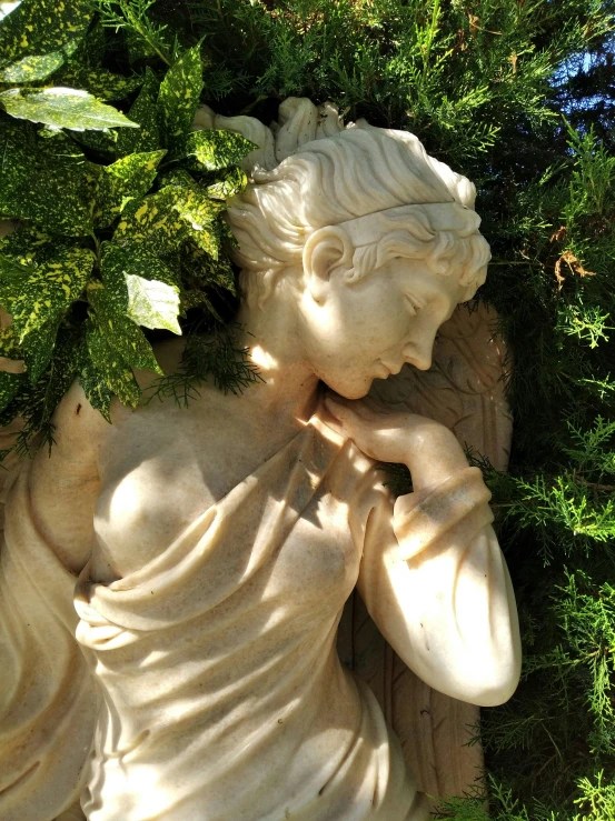 a statue of an angel lying in grass