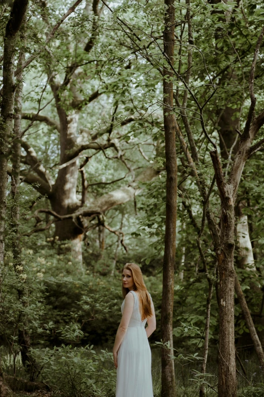 a woman is standing in the middle of a forest