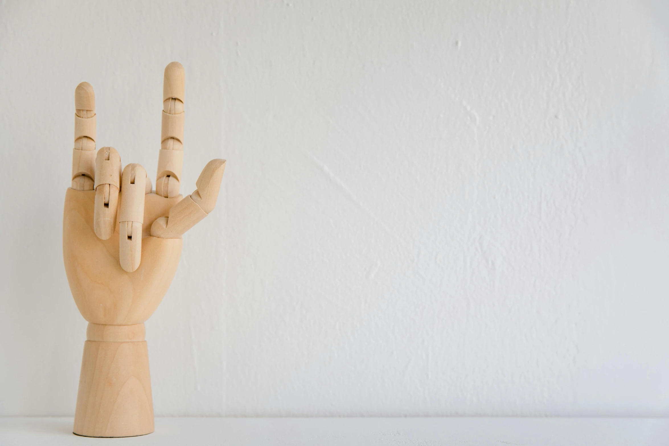 a wood toy hand with fingers showing three different ways