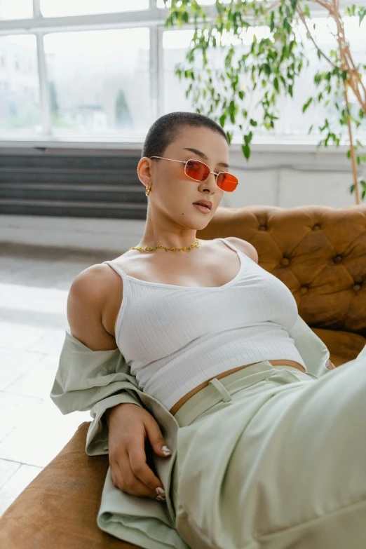 a woman wearing glasses and top sitting on a couch