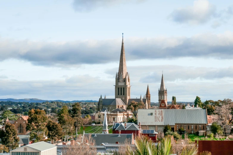 an old cathedral stands in the background of some green rooftops