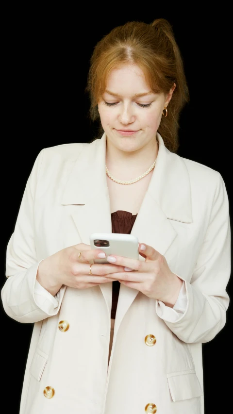 a woman in a white coat using a smart phone